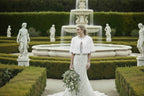 bride wearing a sarah mini mink jacket in pure white in an italianate garden 