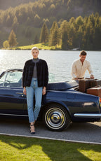 A woman wearing a navy and white colour-blocked mink fur bomber jacket by Lilly e Violetta Furs with collarless design, paired with blue jeans and a grey top.